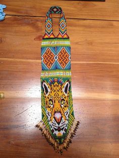 a colorful beaded tiger bag hanging on a wooden floor next to a remote control