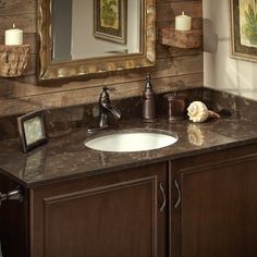 a bathroom sink sitting under a mirror next to a wooden cabinet and wall mounted candle holder