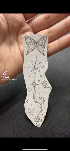 a hand holding a small piece of paper with a butterfly on it's back