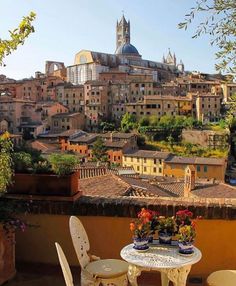 an outdoor table and chairs on top of a roof with the city in the background