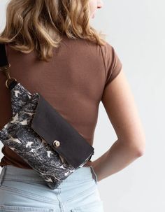 a woman wearing a brown shirt holding a black and white purse with an animal print on it