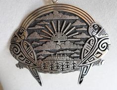 a necklace with two birds on it and the sun in the sky above them, hanging from a silver chain