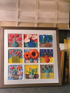 a wooden frame with flowers and plants in it on top of a shelf next to books