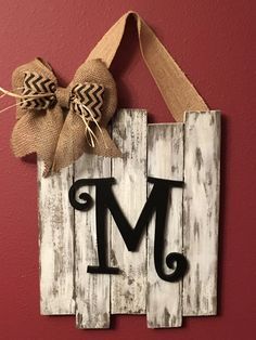 a wooden sign that has the letter m on it and a bow attached to it