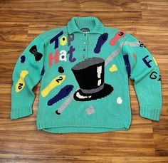 "1990s vintage novelty sweater by Berek. Dance themed hand knit sweater. Slouchy fit with a ribbed knit collar, cuffs and waist. Novelty number buttons down the front. The front features intarsia knit top hat, cane and numbered foot prints. The left sleeve says \"Fred and Ginger\". The right sleeve has numbered foot prints and a bow tie. The back has an intarsia knit dancing couple that must be Fred & Ginger dancing on a cloud. Really incredible craftsmanship on this rare novelty knit.  { LABEL- FABRIC- TAG SIZE } Berek  Cotton | Ramie  No size tags { MEASUREMENTS } Shown on a 5'8\" Mannequin with 33\" Bust- 25\" Waist- 35\" Hips  Bust- 44\" Waist- 40\" Sleeves- 22\" Shoulders- 23\" Total Length- 25\" { CONDITION } Excellent Vintage Condition PLEASE READ BEFORE PURCHASING For best fit, ple 90s Style Knitted Tops For Winter, Hand Knitted Fitted Winter Tops, Winter Hand Knitted Fitted Tops, Hand Knitted Fitted Tops For Winter, Vintage Knit Tops For Winter, 90s Style Winter Knitted Tops, 90s Style Knitted Winter Top, 90s Style Knitted Winter Sweater, Kerropi Sweater