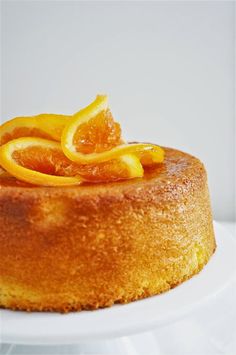 a cake with orange slices on top is sitting on a white plate, ready to be eaten