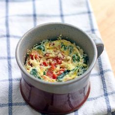 an omelet with tomatoes and spinach in a bowl on a checkered tablecloth