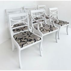 four white chairs sitting next to each other on top of a white floored room