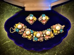 Amazing early 1950s gold filigree panel link Bracelet and Earring Set with Multi-Coloured Pastel Enamel painted flowers, Aurora Borealis Rhinestones and Cream Iridescent Italian Blown Glass globes. Very unique & très delicate to match the times we live in. In excellent condition with working safety chain.  Comes with velvet hardcase display box! Measurements: Each panel is 1" by 1" with a depth of 1/2" Length of bracelet:  6 1/2" Vintage Jeweled Jewelry For Evening, Vintage Multicolor Jewelry With Matching Earrings, Retro Jeweled Wedding Jewelry, Retro Jeweled Gold Jewelry, Retro Gold Jeweled Jewelry, Vintage Multi-stone Multicolor Jewelry, Vintage Jeweled Jewelry For Parties, Multicolor Victorian Jewelry For Formal Occasions, Victorian Multicolor Formal Jewelry