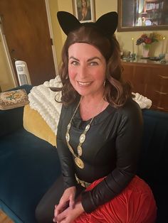 a woman sitting on top of a blue couch wearing a black cat ears headpiece