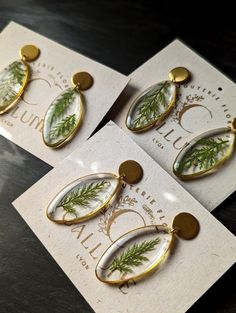 three pieces of jewelry sitting on top of a table next to each other with leaves painted on them