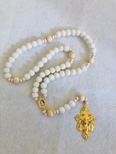 "This soft, beautiful rosary makes the perfect gift for any occasion. Carefully crafted with highest quality materials. The Hail Mary beads are made of 100% sheep's wool felt balls and the Our Father beads are natural wood. The high quality gold toned Crucifix and Centerpiece are absolutely beautifully detailed. This unique crucifix is called a Triple Threat Crucifix because it combines 3 of the most powerful sacramentals of the Church into one piece! There is an indulgence granted by Pope Saint Pius X each time you kiss this crucifix. Die cast for exceptional detail.  Hail Mary Wool Beads: 1 cm diameter Our Father Wood Beads: 12 mm diameter Small Wood Spacer Beads: 6 mm diameter Crucifix: 2 1/8\" Total Length when laid flat: approximately 18 inches" Spiritual Beaded Rosary For Blessing, White Spiritual Rosary Bracelet, White Rosary With Wooden Beads As Gift, White Wooden Beads Rosary As Gift, White Spiritual Rosary Bracelet With 8mm Beads, Adjustable White Rosary With 108 Beads, Spiritual Rosary With 8mm Beads For Blessing, White Rosary With 8mm Beads Crucifix, White Rosary With 8mm Beads For Meditation