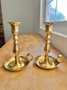 two golden candlesticks sitting on top of a wooden table