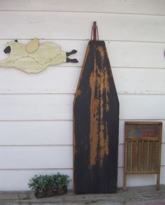 an old wooden boat on the side of a white house with a plant next to it