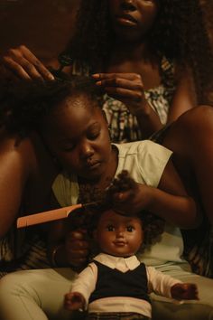 a woman combing her doll's hair while another looks on