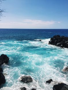 the ocean is blue and clear with waves coming in from the rocks on the shore