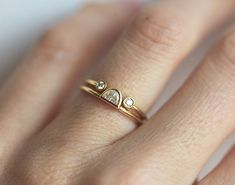 a woman's hand wearing a gold ring with two small diamonds on the band