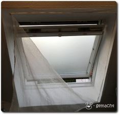 an open window with white curtains hanging from it's side and the skylight above