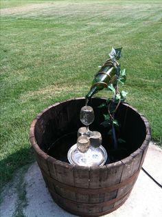 a wooden barrel filled with water sitting on top of a lush green field next to a tree