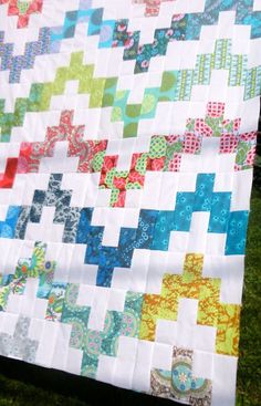 a colorful quilt sitting on top of a lush green field