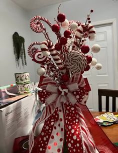 a vase filled with lots of candy canes and candies on top of a table