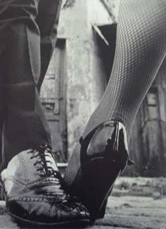 black and white photograph of man and woman's legs with fishnet stockings