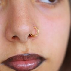 a close up of a woman with a nose ring on her nose and piercing in the middle