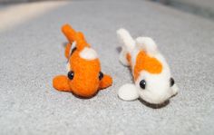 two small orange and white stuffed animals laying on the ground