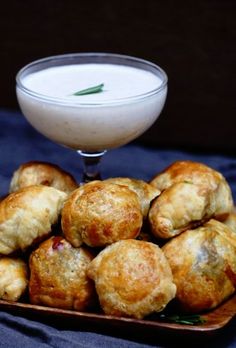 small pastries on a plate next to a bowl of cream and a glass of milk