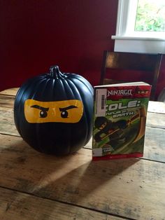 a lego pumpkin sitting on top of a wooden table next to a box of cereal