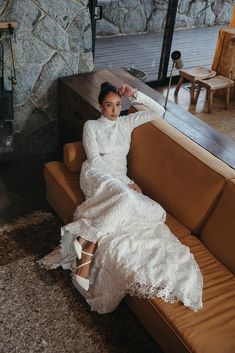 a woman sitting on top of a couch wearing a white dress