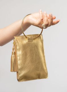 This bag is made from high-quality, super-soft metallic gold leather sourced from a premiere hide house in California. The leather is shipped to New York City, where our bags are produced by expert craftsmen and finished with a smooth zipper, leather tassel, and metal ring. Just big enough for all your essentials, we designed the Ring Wristlet to be your go-to bag for going out! Whether you’re heading to a cocktail party, a concert, or out on the town, slip it on your wrist so your hands are fre Modern Gold Leather Clutch, Everyday Gold Leather Clutch, Chic Gold Leather Clutch, Gold Leather Pouch Clutch, Gold Leather Clutch With Soft Leather, Gold Bags With Smooth Grain For Daily Use, Elegant Gold Clutch With Soft Leather, Gold Soft Leather Clutch, Gold Leather Bag With Smooth Grain