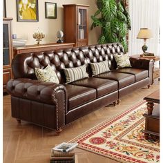 a brown leather couch sitting in a living room next to a wooden table and rug