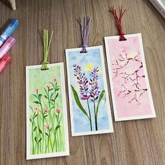 three cards with flowers are sitting on a table next to crayons and markers