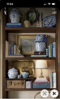 a book shelf filled with books next to a lamp and vases on top of it