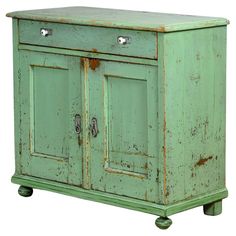 an old green cabinet with two doors and one drawer