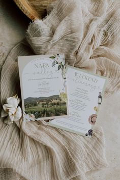 two wedding cards sitting on top of a bed next to a white tulle flower