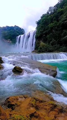 the water is rushing over the rocks and into the river to get to the waterfall