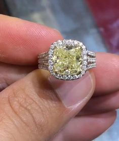 a close up of a person's hand holding a ring with a yellow diamond