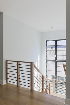 an empty living room with wood floors and white walls, along with wooden railings