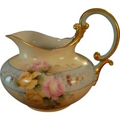 a white and gold vase with flowers painted on it