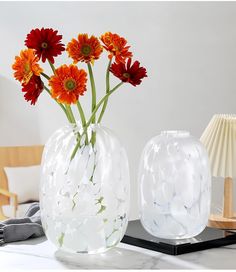 two vases with flowers in them sitting on a table