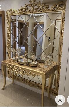 an ornate gold table with mirror and dishes on it