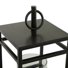 a small black table with a candle holder on it's top and an empty glass plate underneath