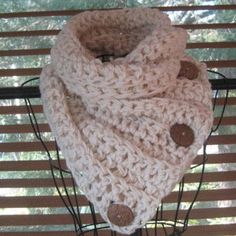 a crocheted scarf with buttons is hanging on a window sill in front of the blinds