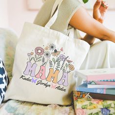 a woman sitting on a couch holding a tote bag with the word mama written in it