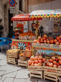 an outdoor fruit stand with oranges and apples