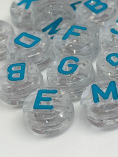 several clear plastic beads with blue letters and numbers on the top one is round in shape