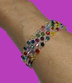 a woman's arm with a bracelet made out of multicolored stones on it