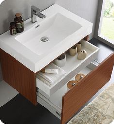 a white sink sitting under a bathroom mirror next to a wooden cabinet with drawers underneath it